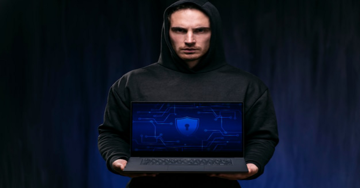 Hacker holding a laptop in hand with a stern expression