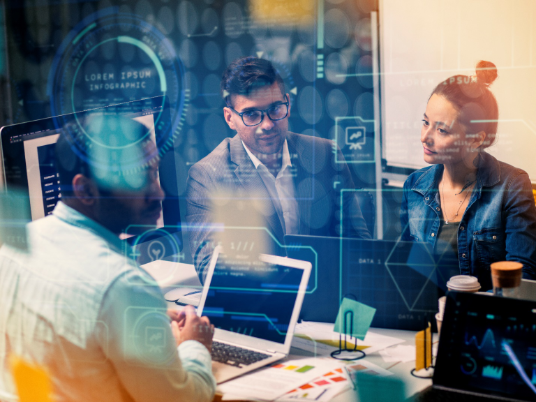 Three people sit together with their laptops with a graphic overlay to symbolize tailored and comprehensive IT solutions as outlined in this Managed IT Services guide