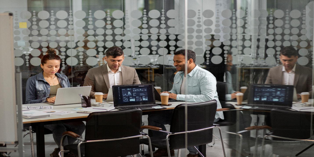 Business team working together with laptops in a glass-walled meeting room
