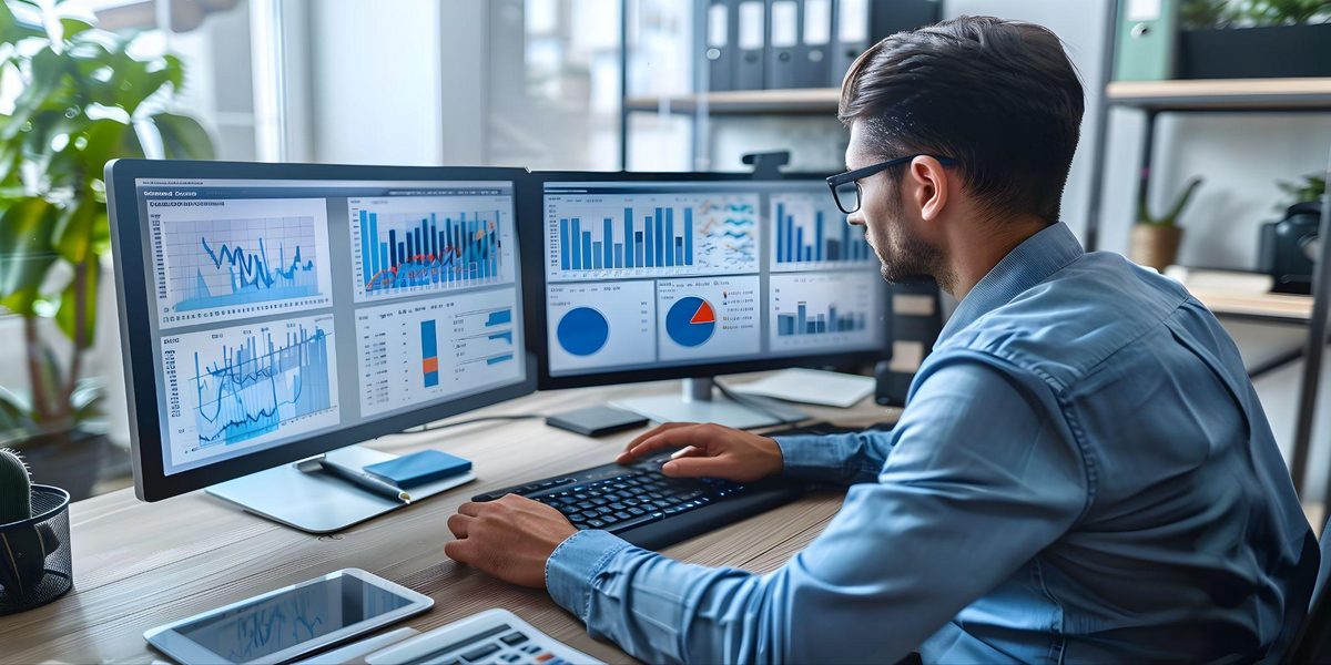 Data analyst reviewing multiple business intelligence dashboards on dual monitors, representing predictive analytics for business decision-making