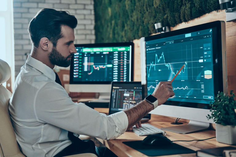 Business professional analyzing financial dashboards on dual monitors, illustrating ERP vs custom software decision-making for accounting and financial systems