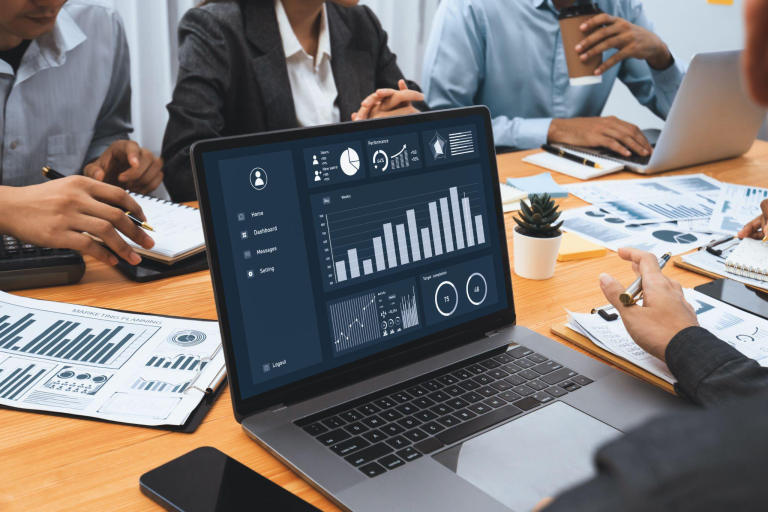 Financial dashboard displayed on a laptop during a team meeting, illustrating predictive analytics in finance for forecasting and performance planning