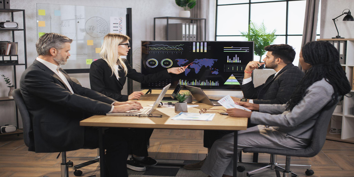 Three people sit around a desk with their laptops, analysing data using software, showing the importance of Managed IT Services for businesses to succeed.