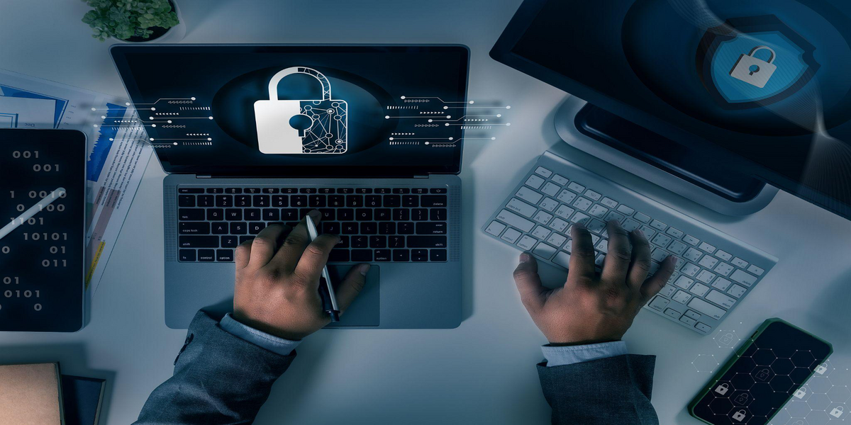 Business professional working on a laptop with a digital lock icon representing common cybersecurity mistakes SMEs make in 2025