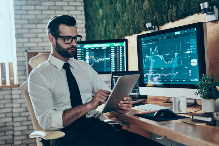 Business professional reviewing financial performance dashboards on dual monitors and tablet, illustrating Sage 300 financial visibility for Canadian SMEs