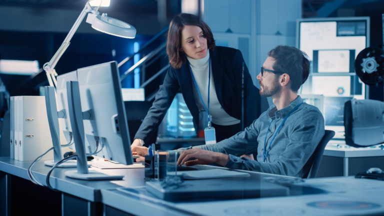 IT professionals reviewing system data on large monitors, illustrating proactive oversight, cyber security awareness, and operational continuity for businesses.