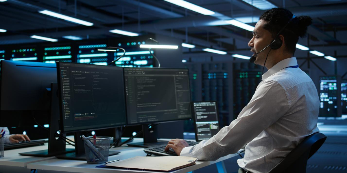 IT technician providing support at a multi-monitor workstation in a secure data center