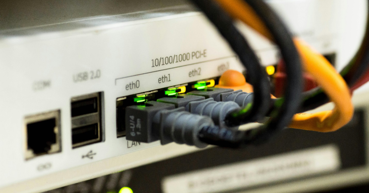 Ethernet cables connected to a white switch hub with illuminated lights, emphasizing Network Infrastructure Security.