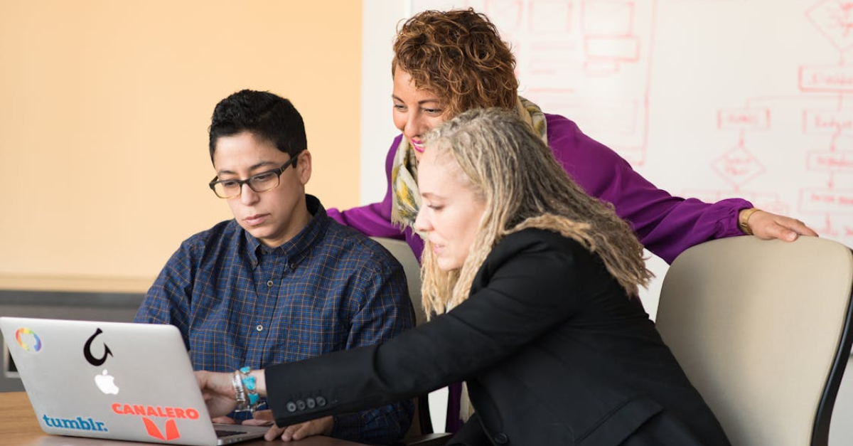 Three people in an office looking at a laptop screen