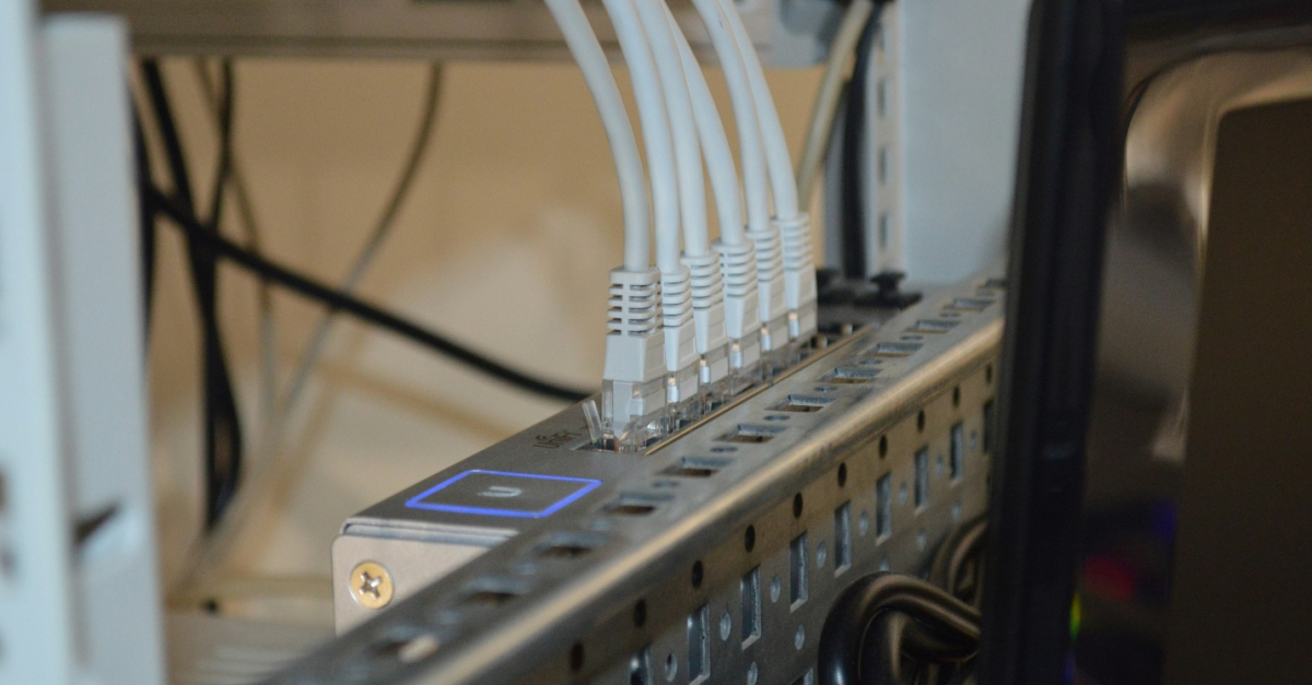 A close-up image showing six white ethernet cables neatly connected to a machine, illustrating the meticulous setup required when setting up IT headquarters and staying on point with the IT management trends.