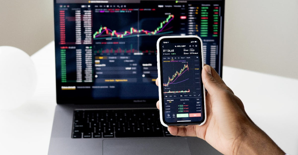 Hand holding a phone screen in front of a laptop screen showing data against black, emphasizing how Sage Consultants can assist with systems like Sage 300 or Sage Intacct for easier reconciliation of financial data.